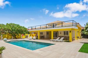 a villa with a swimming pool and a house at Wayaca 231 in Oranjestad