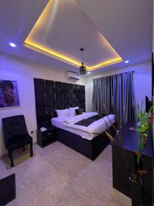 a bedroom with a king sized bed and a chair at LEON'S HOTELS and SUITES OWERRI in Owerri