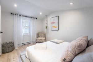a white bedroom with a bed and a chair at LAO Lodge by Gestion ELITE in Mont-Tremblant