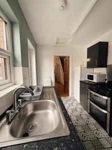 eine Küche mit Spüle und Mikrowelle in der Unterkunft Rock Ferry home in Birkenhead