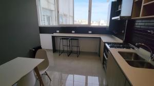 马德普拉塔Alquileres Corrientes的带水槽和带凳子的柜台的厨房