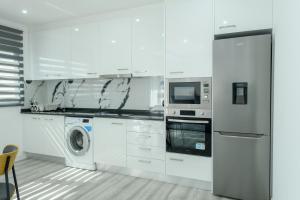 PrainhaEdifício Yes, Luxury 2 Bed Apartments, Praia, Cape Verde with Balcony and AC的配有白色橱柜、洗衣机和烘干机的厨房