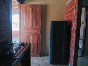 a kitchen with a wooden door and a refrigerator at Casa Cantinho do Céu Santo Amaro MA in Santo Amaro