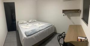 a small bed in a room with a wooden table at Aquarius Hoteis Ltda in Canarana