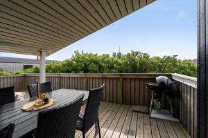 a patio with a table and chairs on a deck at 641-Hvide-Sande-Julianevej-13 in Bjerregård