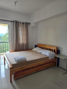 Una cama en un dormitorio con una ventana grande. en Studio Unit near Mines View Park, Baguio City, en Baguio 4 fotos más