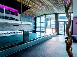a room with a swimming pool with a tv and glass windows at Chalet H Königsleiten in Königsleiten