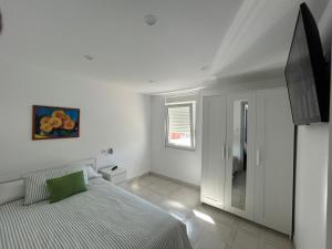 una camera da letto bianca con un letto e una televisione di Casa Carmen e do Hilario a Ponte Do Porto