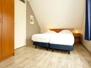 Un dormitorio con una cama y suelo de madera. en Charming forest house surrounded by a garden, en Heel