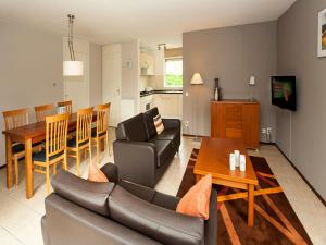 una sala de estar con un sofá y una mesa en Charming forest house surrounded by a garden, en Heel