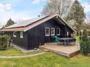 Smidstrup5 star holiday home in Gilleleje的一个带桌子和甲板的黑色小屋