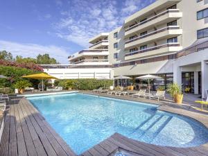 a swimming pool in front of a building at Mercure Hyères Centre Côte d'Azur in Hyères