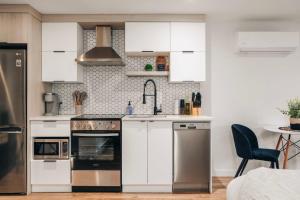 een keuken met witte kasten en roestvrijstalen apparaten bij LAO LOFT 105 by Gestion ELITE in Mont-Tremblant