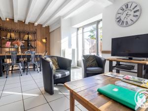 VihiersGîte moderne avec piscine en Anjou, proche Saumur et Cholet, idéal pour familles et groupes - FR-1-622-30的客厅里有一张桌子，墙上挂着一个钟