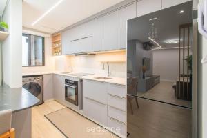 a kitchen with white cabinets and a stainless steel refrigerator at Aptos completos em prédio com piscina a 400m da Praia de Piçarras - BACs in Piçarras