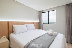 a bedroom with a white bed with a window at Aptos completos em prédio com piscina a 400m da Praia de Piçarras - BACs in Piçarras +36 photos