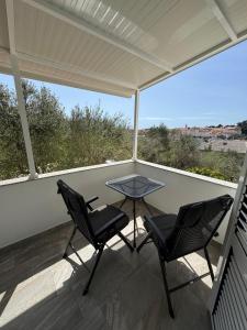 a patio with two chairs and a table on a balcony at Rooms by the sea Rab - 18786 in Rab