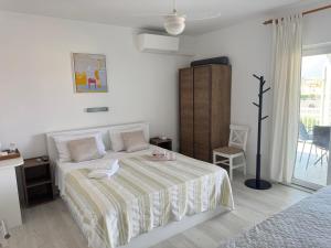 a white bedroom with a bed with a striped blanket at Rooms by the sea Rab - 18786 in Rab