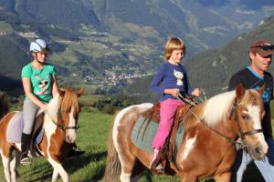 Un par de personas montando caballos en una colina en Haflingerhof, en Fiss