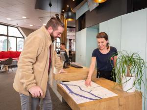 ibis Nantes Centre Tour Bretagne في نانت: رجل وامرأة يقفان في مكتب