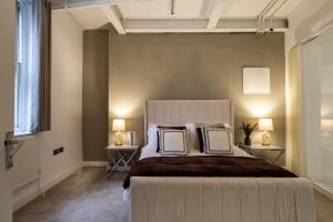 a bedroom with a large white bed with two tables at Skyway Luxury Stay with Jacuzzi in Bradford