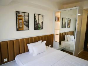 バタム・センターにあるPollux Habibie Apartment Batamの白いベッドと鏡のある寝室 +68枚の写真