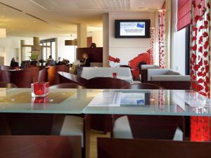 un restaurante con mesa y sillas y gente de fondo en ibis Antwerpen Centrum, en Amberes