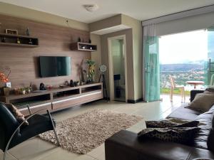 a living room with a couch and a flat screen tv at Refúgio Escarpas do Lago Mirante 1702 in Capitólio