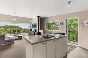 Waipu CoveTreetop Break - Waipu Cove Holiday Home的带水槽的厨房和客厅