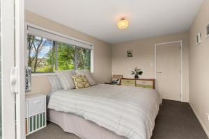 Waipu CoveTreetop Break - Waipu Cove Holiday Home的一间卧室，里面有一张床和一扇窗户。