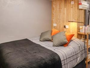 un letto con cuscini arancioni e grigi in una stanza di The Snug a Y Felinheli