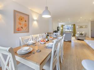 uma sala de jantar com uma mesa de madeira e cadeiras brancas em Lodge 74 Una em Carbis Bay