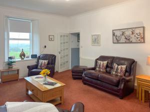 a living room with two leather chairs and a coffee table at Muirston Farmhouse - Uk44977 in Ochiltree