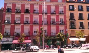 un gran edificio rosa con motos estacionadas frente a él en Hostal Santo Domingo, en Madrid