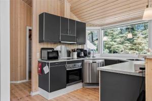 Una cocina con electrodomésticos de acero inoxidable y una gran ventana. en HA141-Hals-Gyvelvej-3-B, en Hals