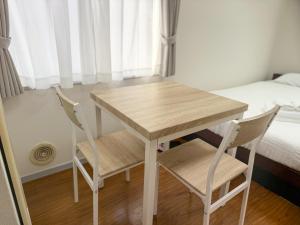 SUNCOURT Komachi في هيروشيما: طاولة وكرسيين في غرفة بها سرير