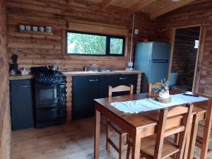 a kitchen with a stove and a table in a cabin at Complejo de Cabañas Pura Vida in Balneario Reta