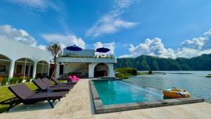 a house with a swimming pool next to a body of water at Lushy Kintamani in Kubupenlokan