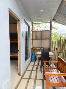 un porche avec un banc en bois et une table dans l'établissement R&C Transient Extension, à El Nido