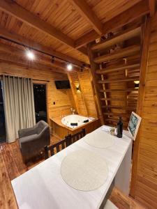 a room with a tub and a table and a chair at Cabana Encanto da Mata in Santa Maria do Erval