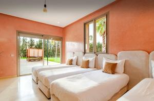 Oulad MazougVilla privée sans vis-à-vis,Padel,Tennis, Five的配有橙色墙壁和窗户的客房内的三张床 更多84张照片