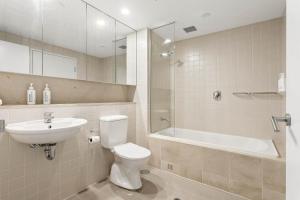 a bathroom with a toilet and a sink and a tub at Belle Escapes - Waves at The Bay in Glenelg +6 photos
