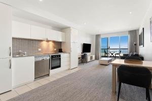 a kitchen and living room with a view of the ocean at Belle Escapes - Waves at The Bay in Glenelg