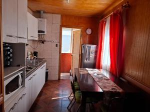 a kitchen with a wooden table and a red curtain at Cabañas San Sebastián 2 in Angachilla