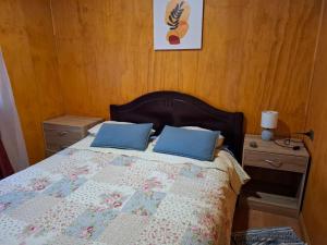 a bedroom with a bed with blue pillows on it at Cabañas San Sebastián 2 in Angachilla