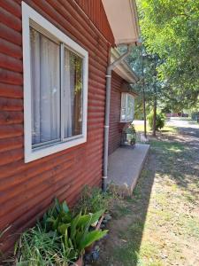 a red house with a porch and a window at Cabañas San Sebastián 2 in Angachilla
