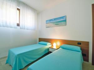 two beds in a room with blue sheets at Apartment with garden in Villasimius in Villasimius