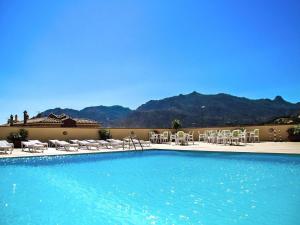 a large swimming pool with chairs at Apartment with garden in Villasimius in Villasimius