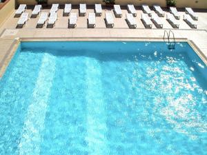 a swimming pool with chairs and a swimming pool at Apartment with garden in Villasimius in Villasimius