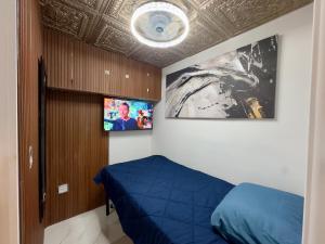 una camera da letto con un letto blu e una TV a schermo piatto di Lux Pod Room a West Palm Beach